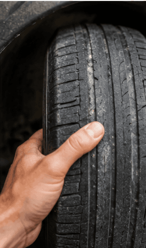Technician inspecting worn vehicle tyre tread